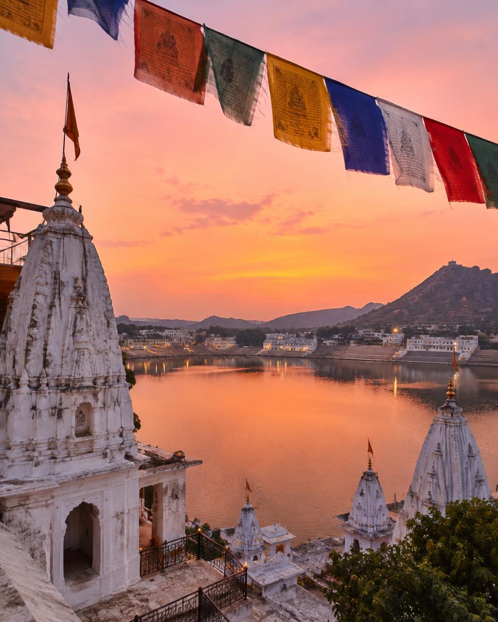 Prayer flags and temple spires over Pushkar lake in Rajasthan at dusk